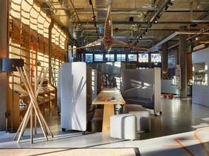 Ein moderner Büroarbeitsplatz mit hohen Decken, freiliegenden Lüftungsrohren und einem großen Fenster, das natürliches Licht hereinlässt.