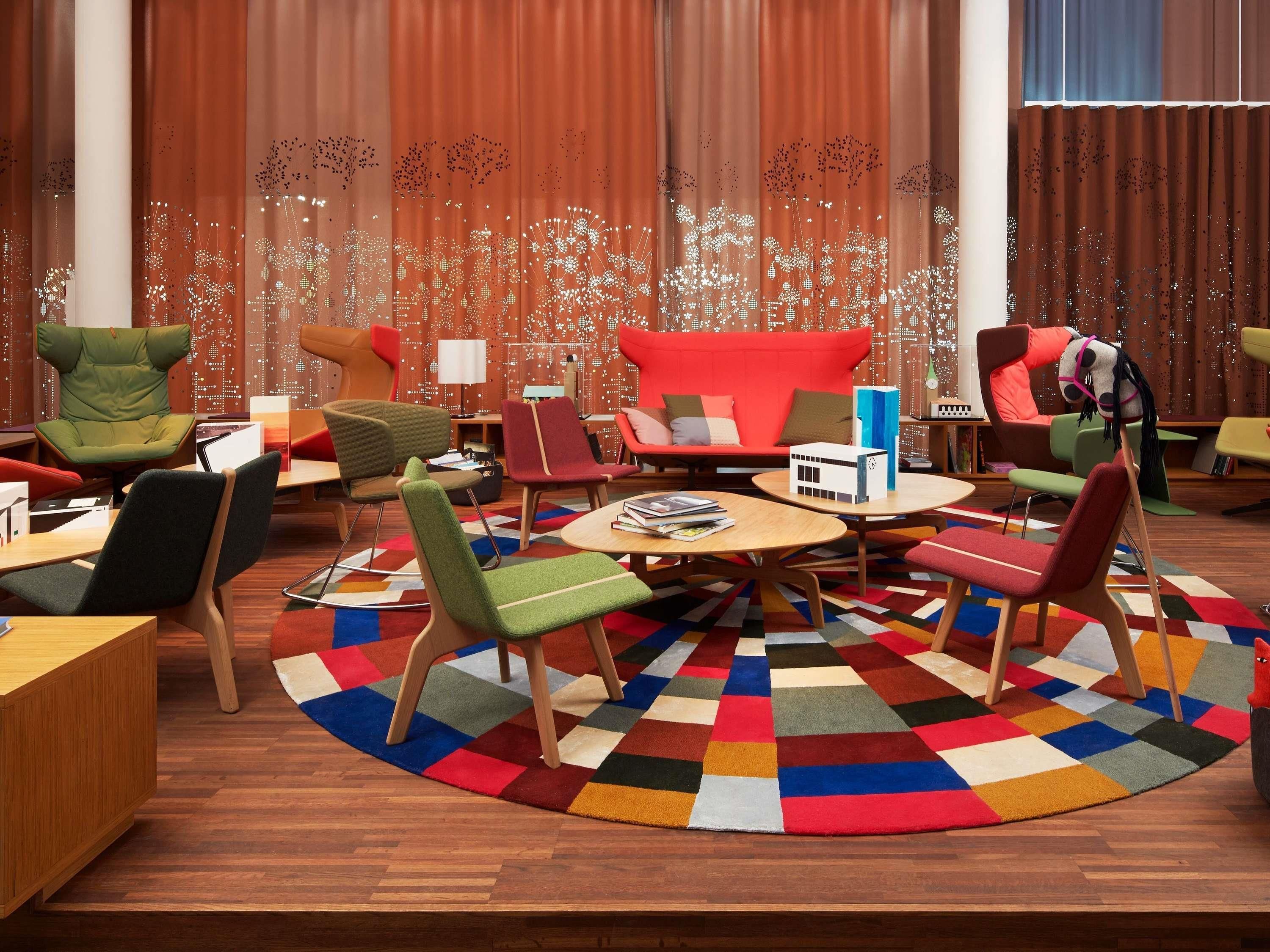 A modern lounge area with multiple seating options, a central coffee table, and a patterned rug.