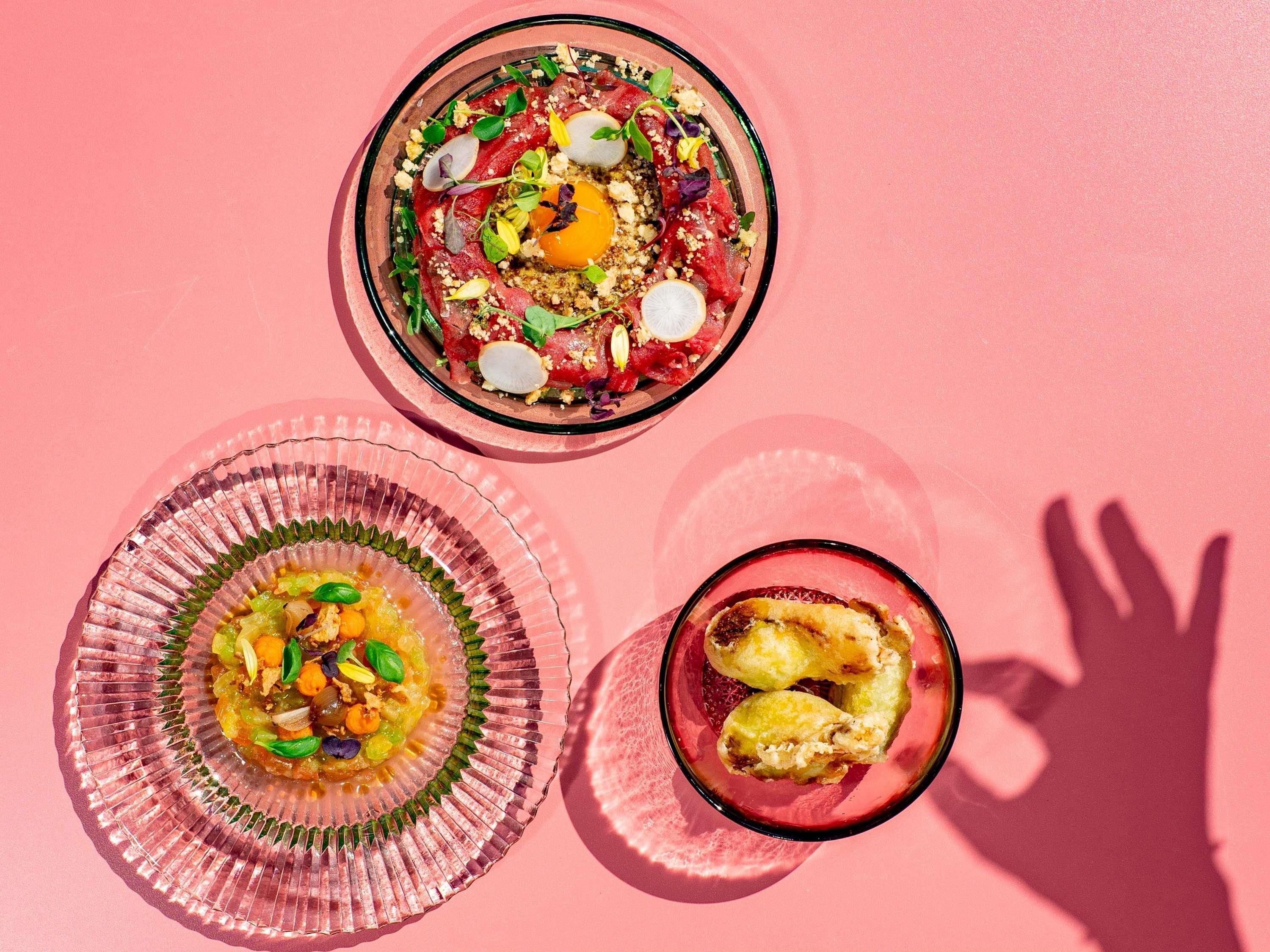 Tres platos sobre una superficie rosa.