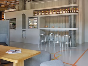 A modern bar area with stools, a refrigerator, and shelves of bottles.