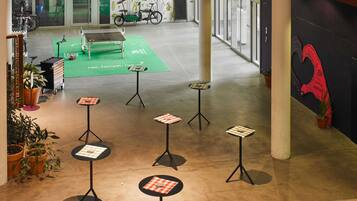 An indoor space with tables and chairs, a green running track, and bicycles.
