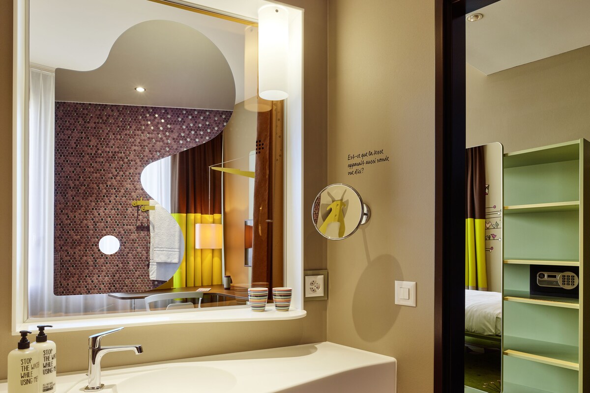 Une salle de bain avec un grand miroir, un lavabo et un meuble-lavabo doté d’étagères.