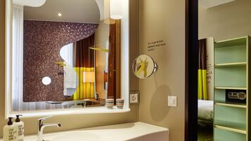 A bathroom with a large mirror, a sink, and a vanity with shelves.