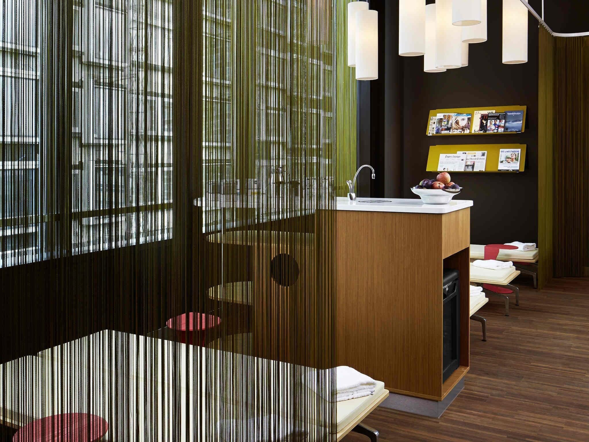 Un interior moderno con mostrador de madera, lavamanos y zona de comedor con mesa y sillas.