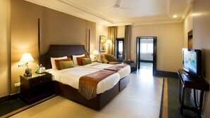 A hotel room with a large bed, bedside lamps, a TV, and a ceiling fan. - Ganga Lahari, Haridwar (Haridwar)