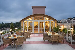An outdoor dining area with wicker furniture and a glass enclosure. - Ganga Lahari, Haridwar (Haridwar)