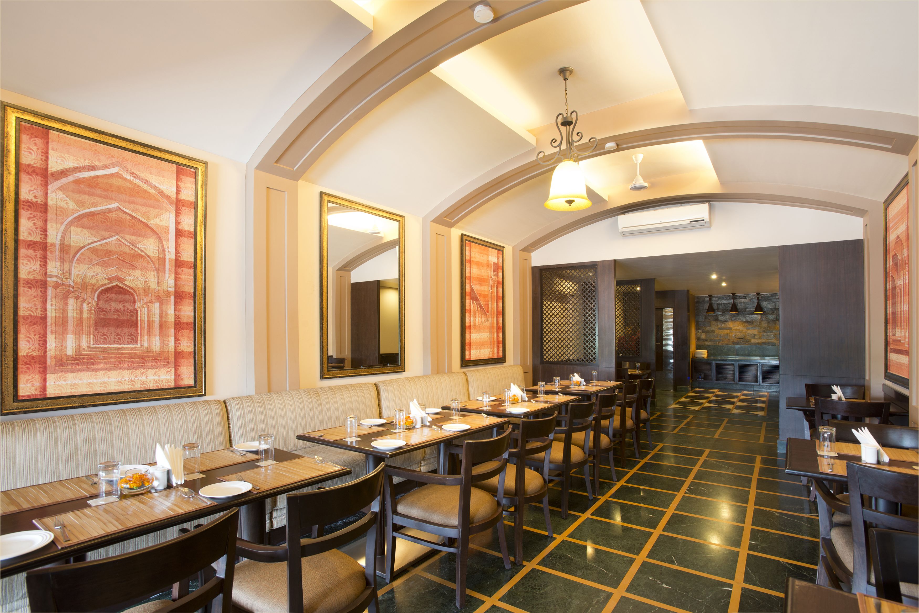 A restaurant with high tables and booths, a patterned floor, and a chandelier.