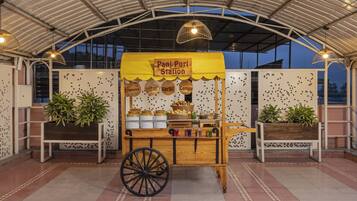 Un puesto de Pani Puri con un carrito, plantas en macetas y un cartel.