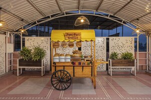 Un puesto de Pani Puri con un carrito, plantas en macetas y un cartel.
