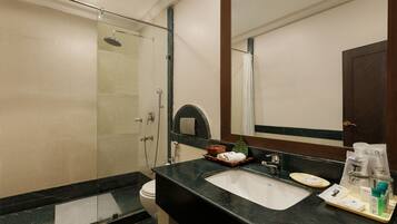 A modern bathroom with a glass-enclosed shower, a sink with toiletries, and a large mirror.