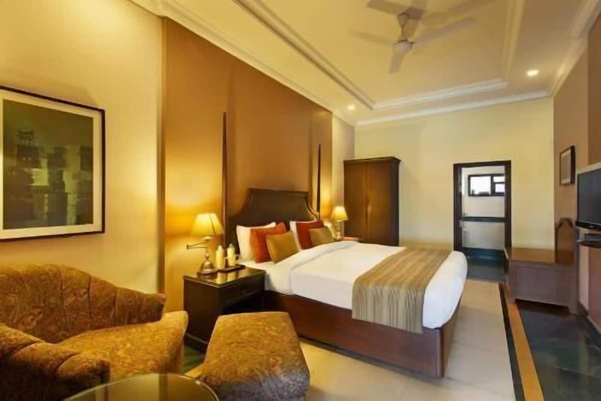 A hotel room with a bed, a sofa, a TV, and a desk.