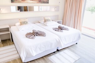Una habitación de hotel con dos camas, un ventanal grande, un espejo y una mesita de noche.
