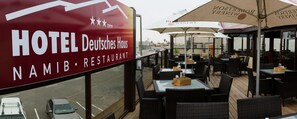 Vista del restaurante Hotel Deutsches Haus Namib con mesas al aire libre y sombrillas.