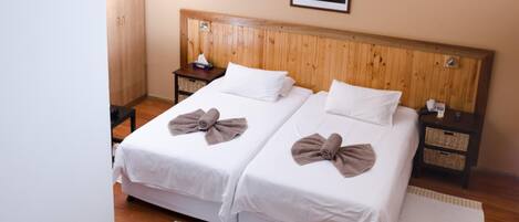 Ein Doppelzimmer mit zwei Betten, einem Holzkopfteil, Nachttischen und einem Wandbild.