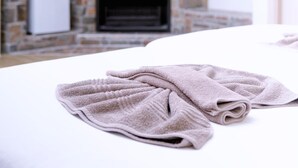 Ein Schlafzimmer mit Kamin aus Stein, einem Bett mit weißem Kopfteil und zwei Handtüchern auf dem Bett.