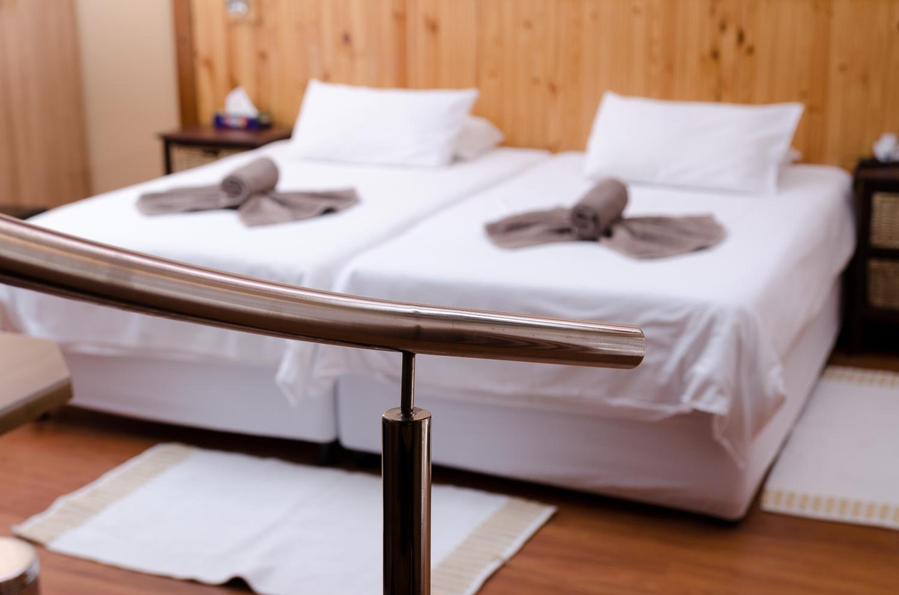 A hotel room with two beds, wooden headboard, white bedding, and a metal railing.
