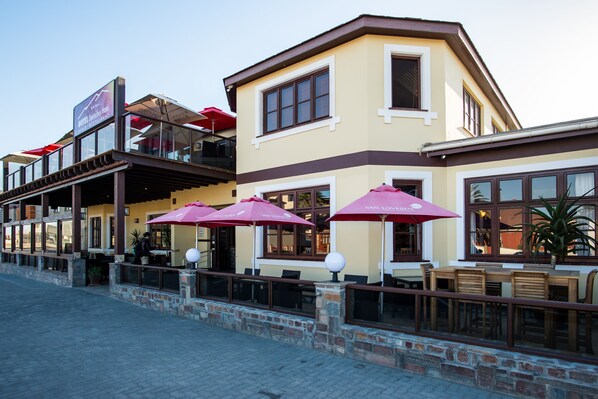 A hotel with outdoor seating, a sign for 'Van de Velde Hotel', and a stone facade.