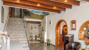 Eine Treppe mit Steinstufen, eine Holzbalkendecke, ein Essbereich mit Stühlen und Tisch sowie eine Rezeption.