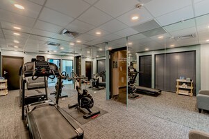 Un gimnasio con cintas de correr, bicicletas estáticas y equipo de ejercicio.