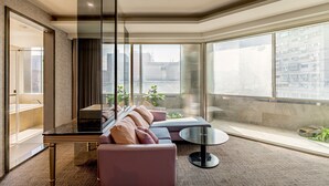 A modern hotel room with a large window, a sofa, a small table, and a glass partition. - HOTEL GEIGHT TAIPEI (New Taipei City)
