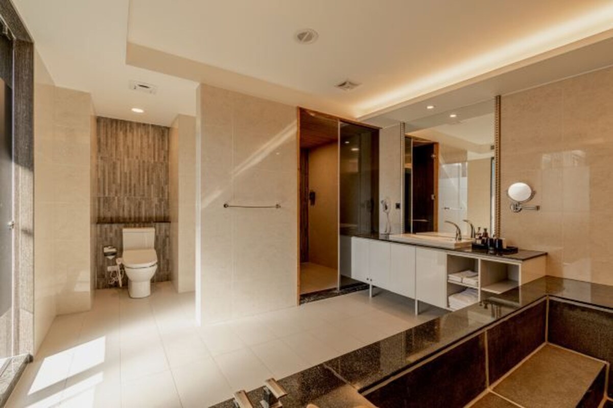 Un baño moderno con un espejo grande, un tocador con lavabo y un inodoro.