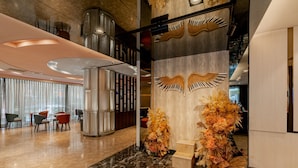 A modern lobby with a marble floor, seating area, decorative wall panels, and a staircase. - HOTEL GEIGHT TAIPEI (New Taipei City)