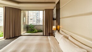 A hotel room with a large bed, a view through a glass door to an outdoor balcony, and a wall-mounted lamp. - HOTEL GEIGHT TAIPEI (New Taipei City)