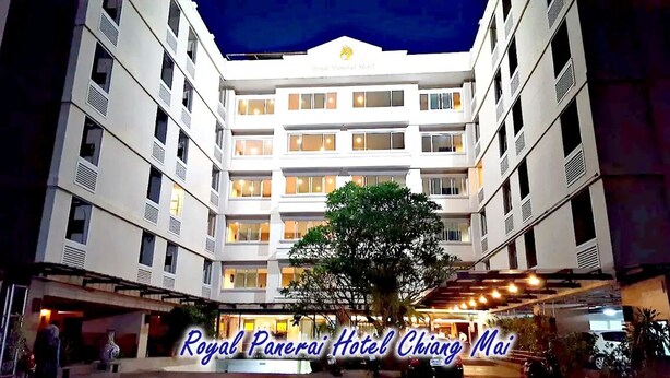 A multi-story hotel with a central courtyard, balconies, and a well-lit entrance. - Royal Panerai Hotel (Chiang Mai)