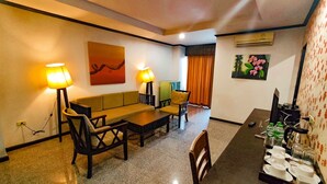 A hotel room with a dining area, two lamps, a sofa, a table, and a tray with cups and glasses. - Royal Panerai Hotel (Chiang Mai)