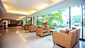 A spacious lobby with wicker furniture and large windows offering a view of the street. - Royal Panerai Hotel (Chiang Mai)