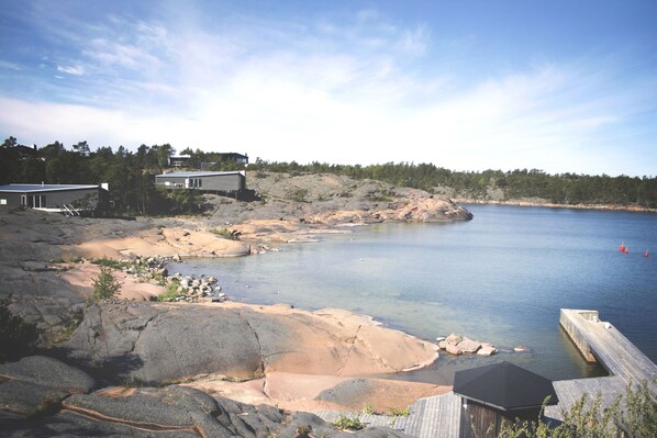 A lakeside property with a dock, rocky shoreline, and a building with a large window overlooking the water.