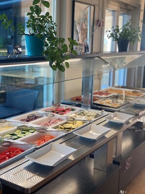 A buffet with various food options, a potted plant, and a glass partition.