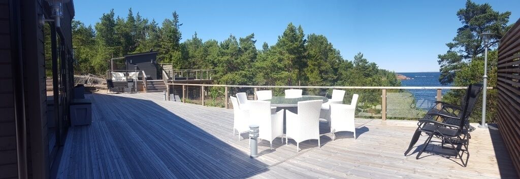 Una terraza de madera con muebles de exterior y vista al océano.