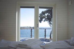 Una habitación con cama y vista al mar a través de un ventanal corredera.