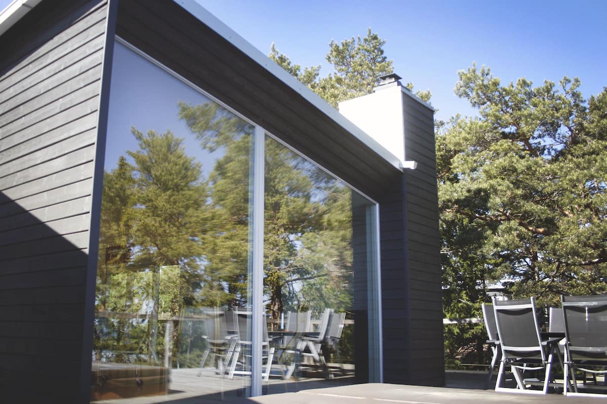 A modern building with large glass windows and a patio area with chairs.