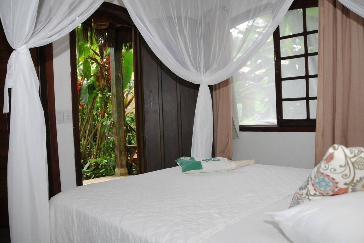 Un dormitorio con cama, ventana con cortinas y vistas a zonas verdes.