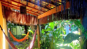A room with a hammock, lush plants, and a stone wall. - Pousada Magia Verde (Paraty)