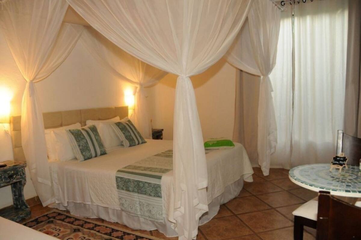 Un dormitorio con cama, mesita de noche, una pequeña mesa y una silla.