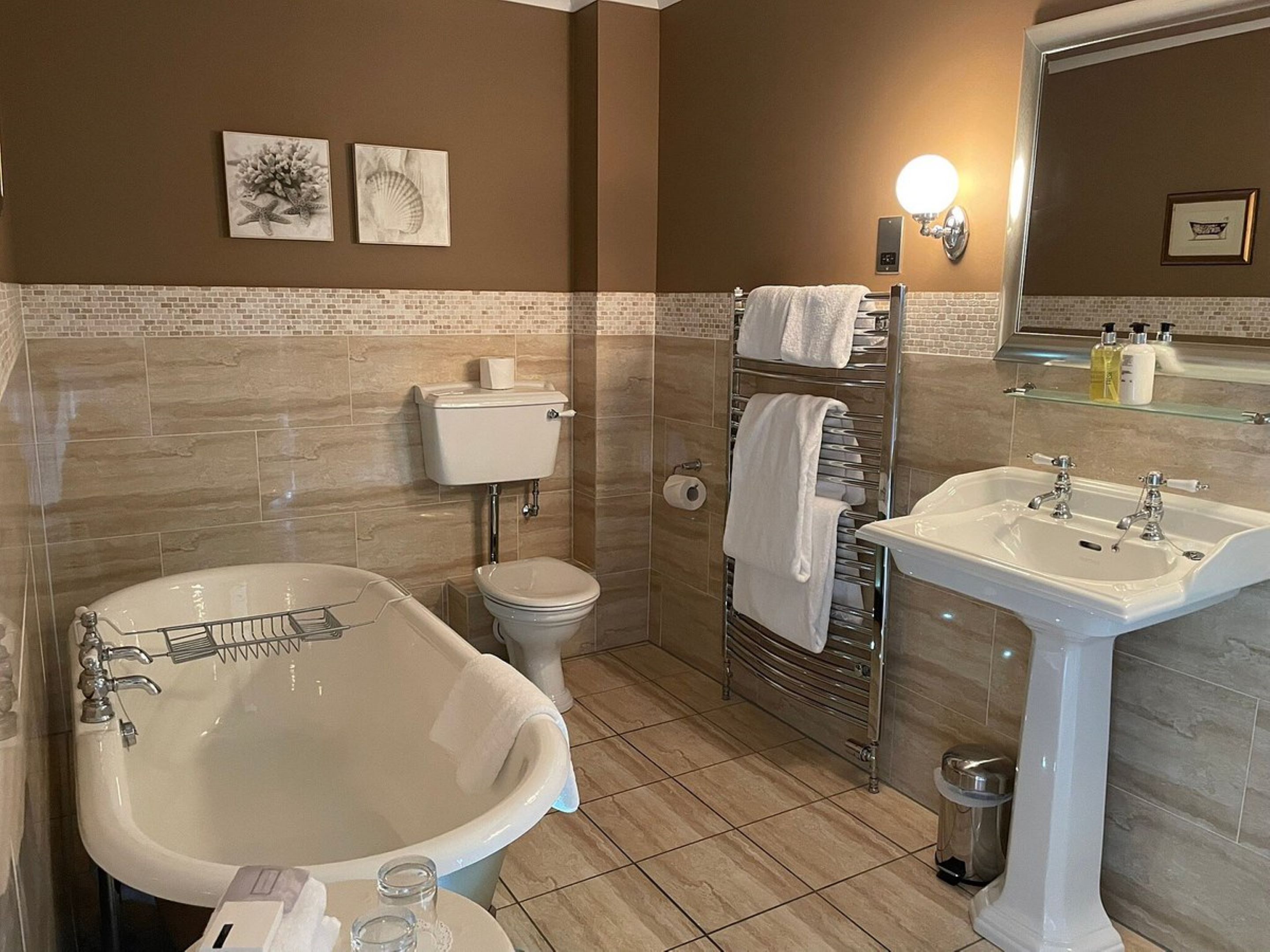 Een badkamer met een vrijstaand bad, toilet, wastafel en handdoekhouder.