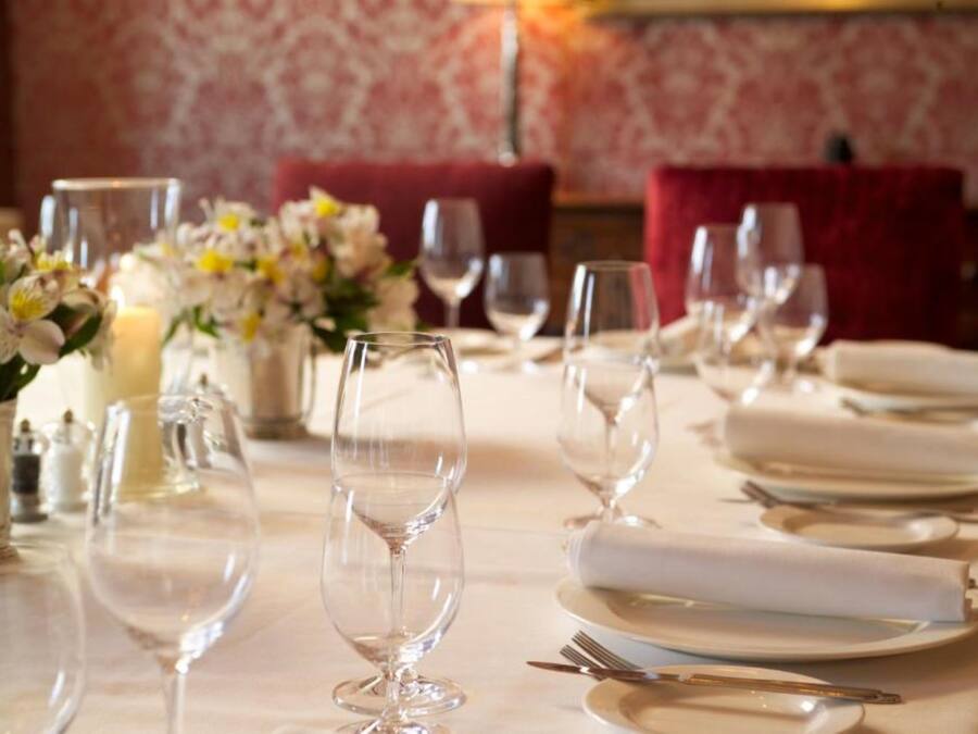 Une table à manger dressée avec des nappes blanches, de la vaisselle en verre transparent et des serviettes pliées avec soin.