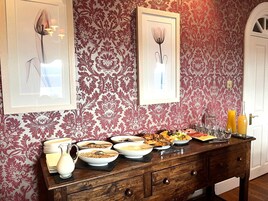 Un bufé de desayuno con diversos platos y una pared decorativa con papel tapiz floral.
