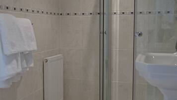 A modern bathroom with a glass-enclosed shower, a white sink, and a toilet.