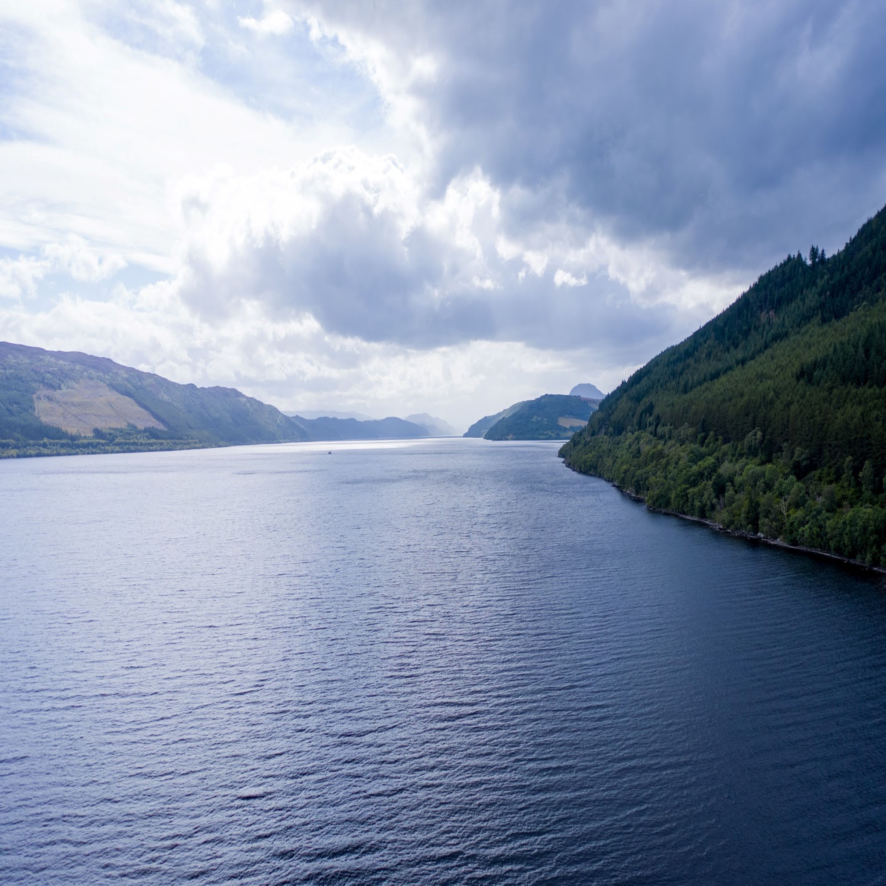 A large body of water surrounded by forested hills.