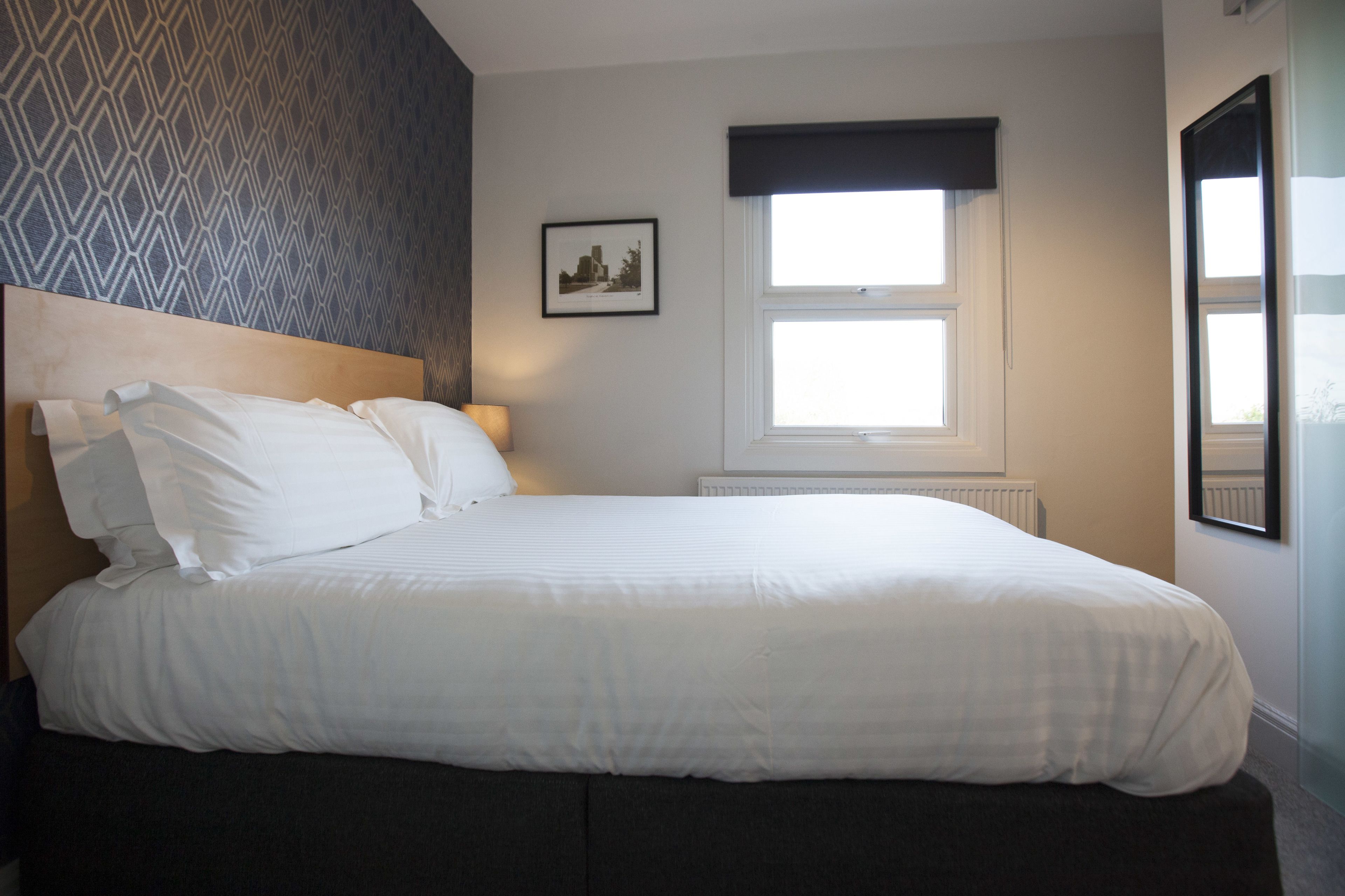 A neatly made bed with white linens in a hotel room.