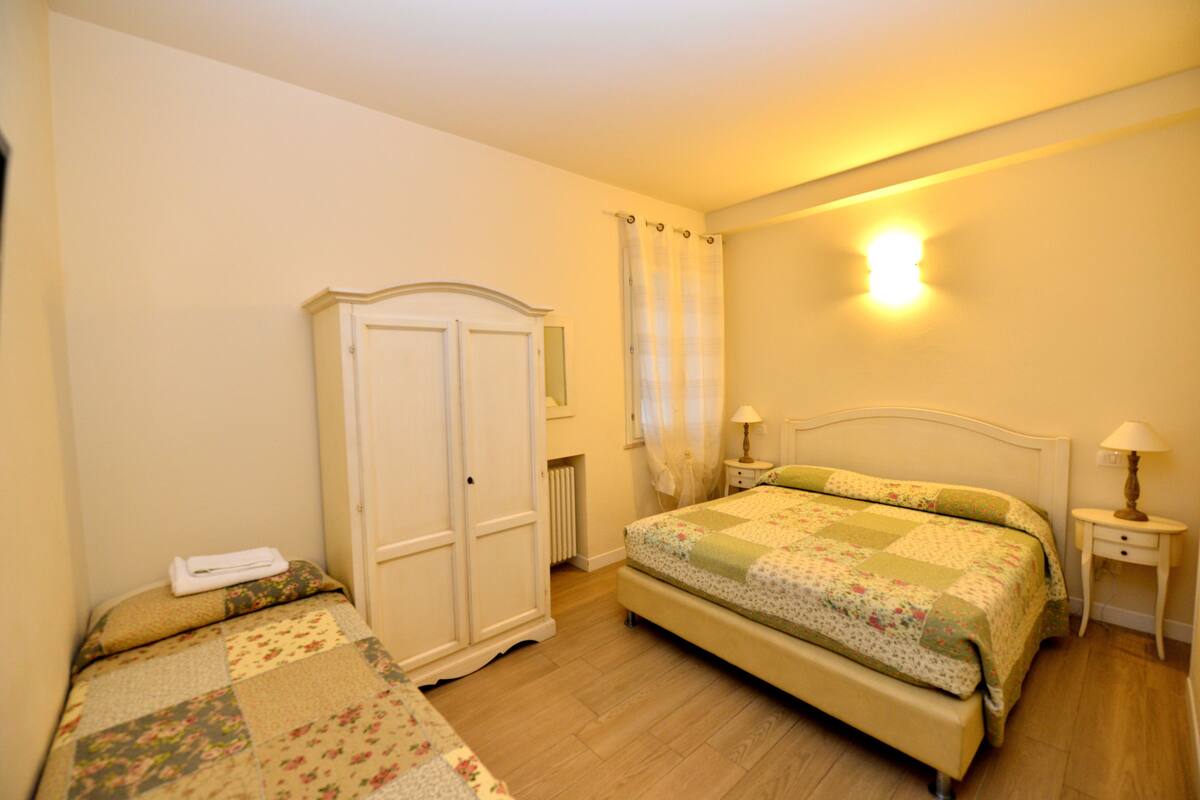 Ein Schlafzimmer mit Bett, Kleiderschrank, Nachttisch und Lampe.