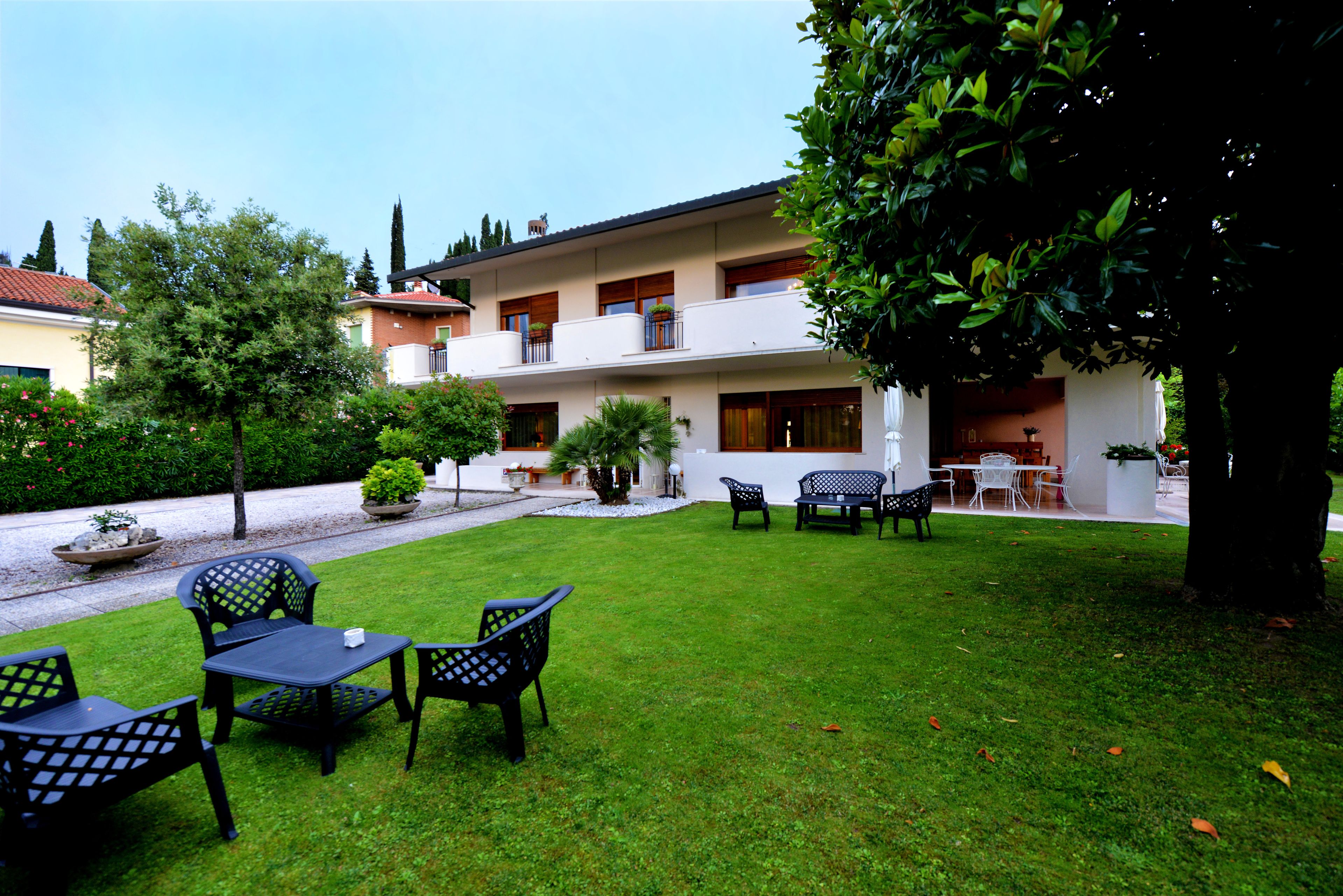 Un patio con césped, mobiliario exterior y un edificio con balcones y ventanas.