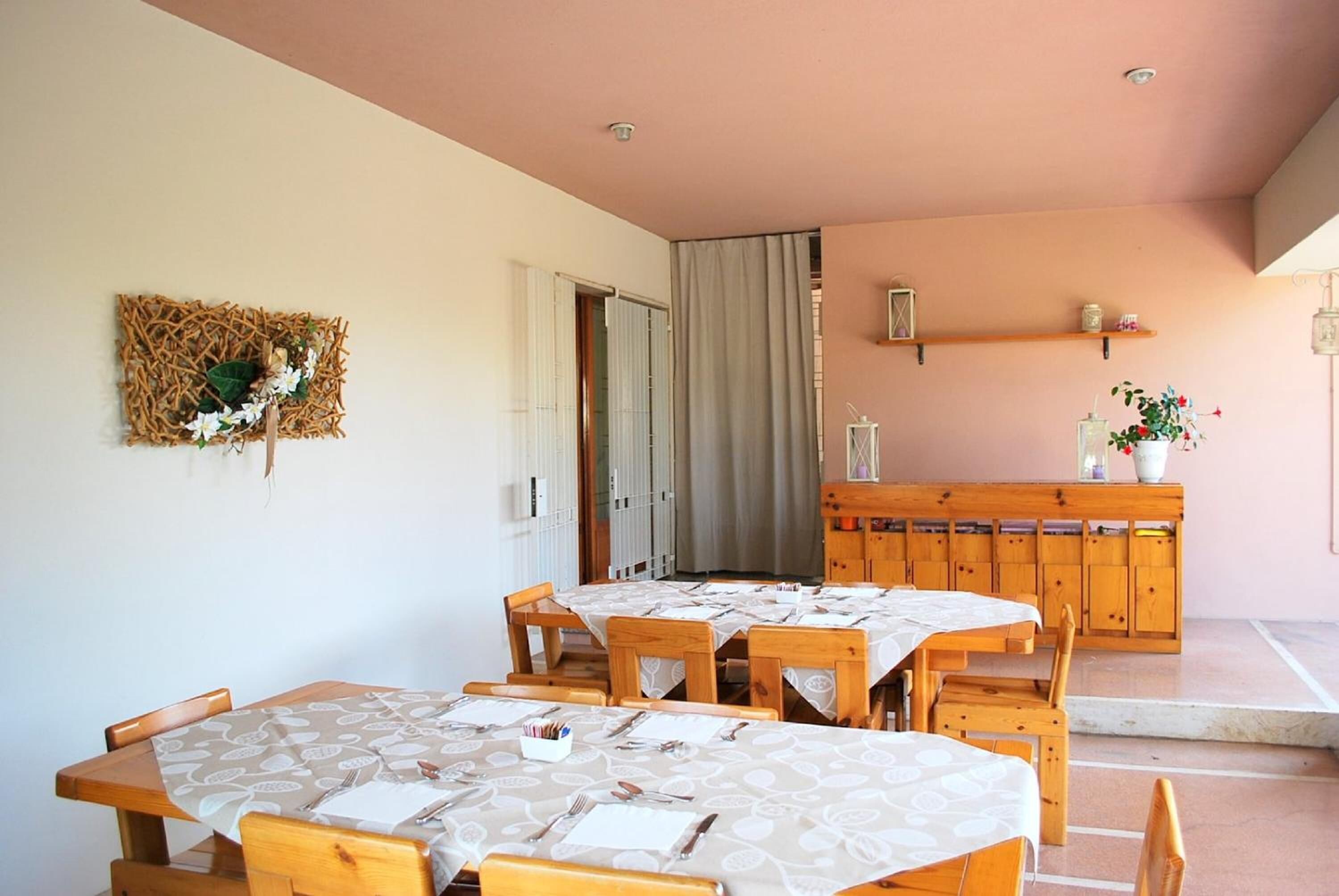 Un comedor con mesas y sillas de madera, un adorno en la pared y un mueble de madera con estantes.