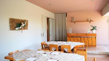 Un comedor con mesas y sillas de madera, un adorno en la pared y un mueble de madera con estantes.