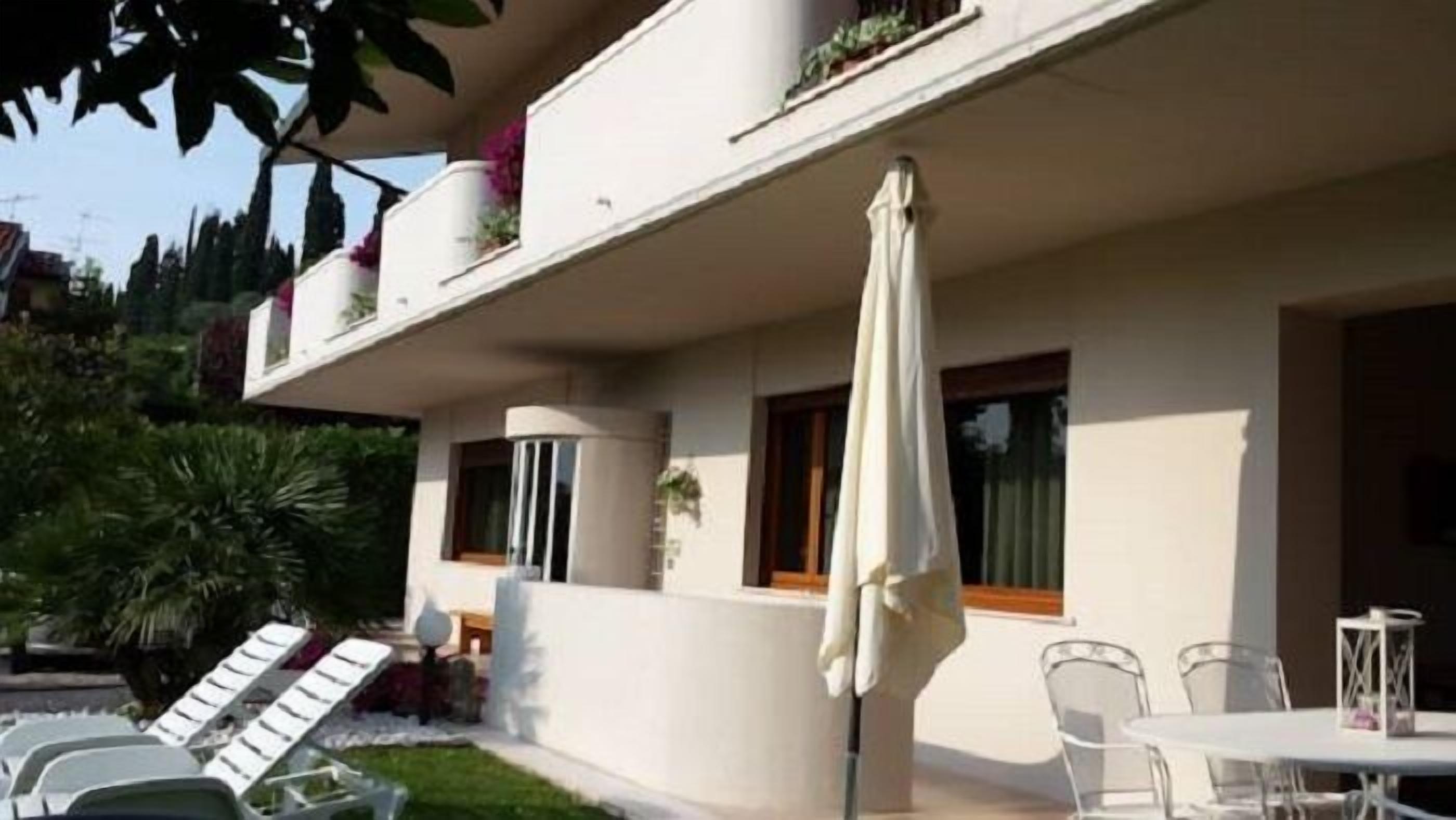 A modern two-story building with a balcony, outdoor seating, and a covered patio area.