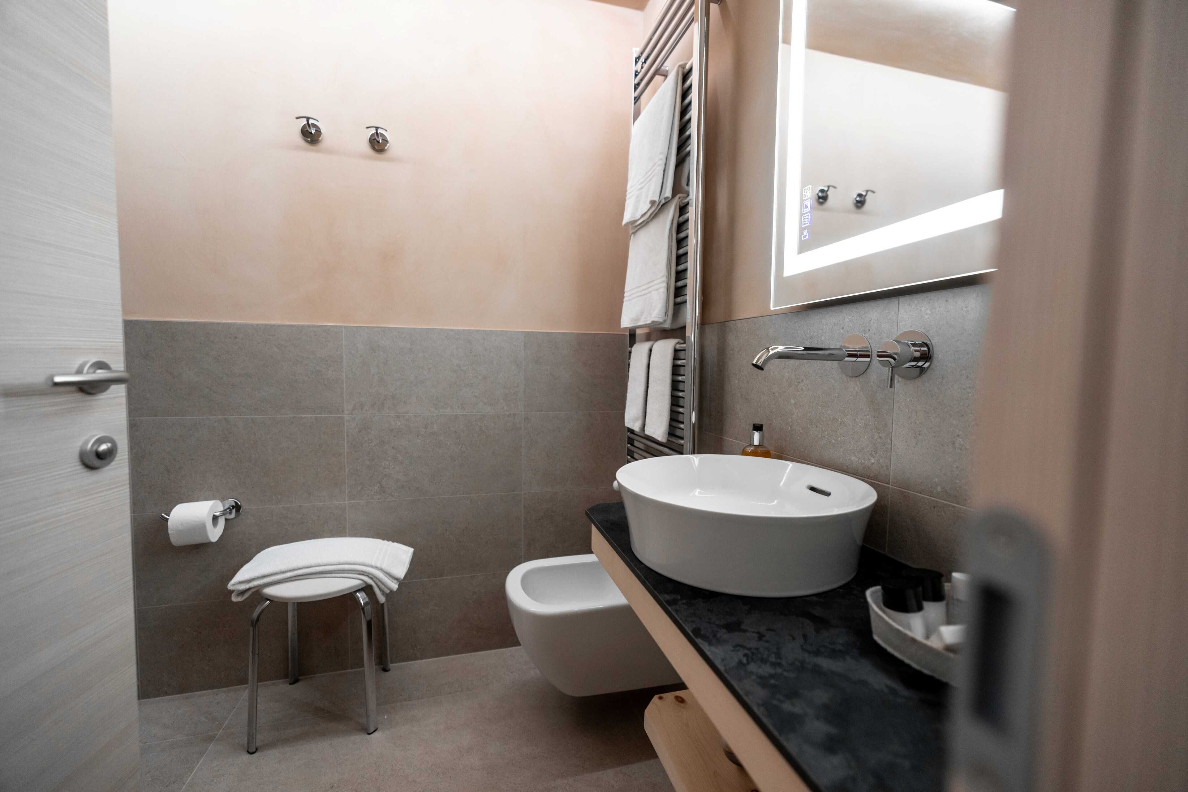 A modern bathroom with a toilet, bidet, and a sink with a mirror above it.